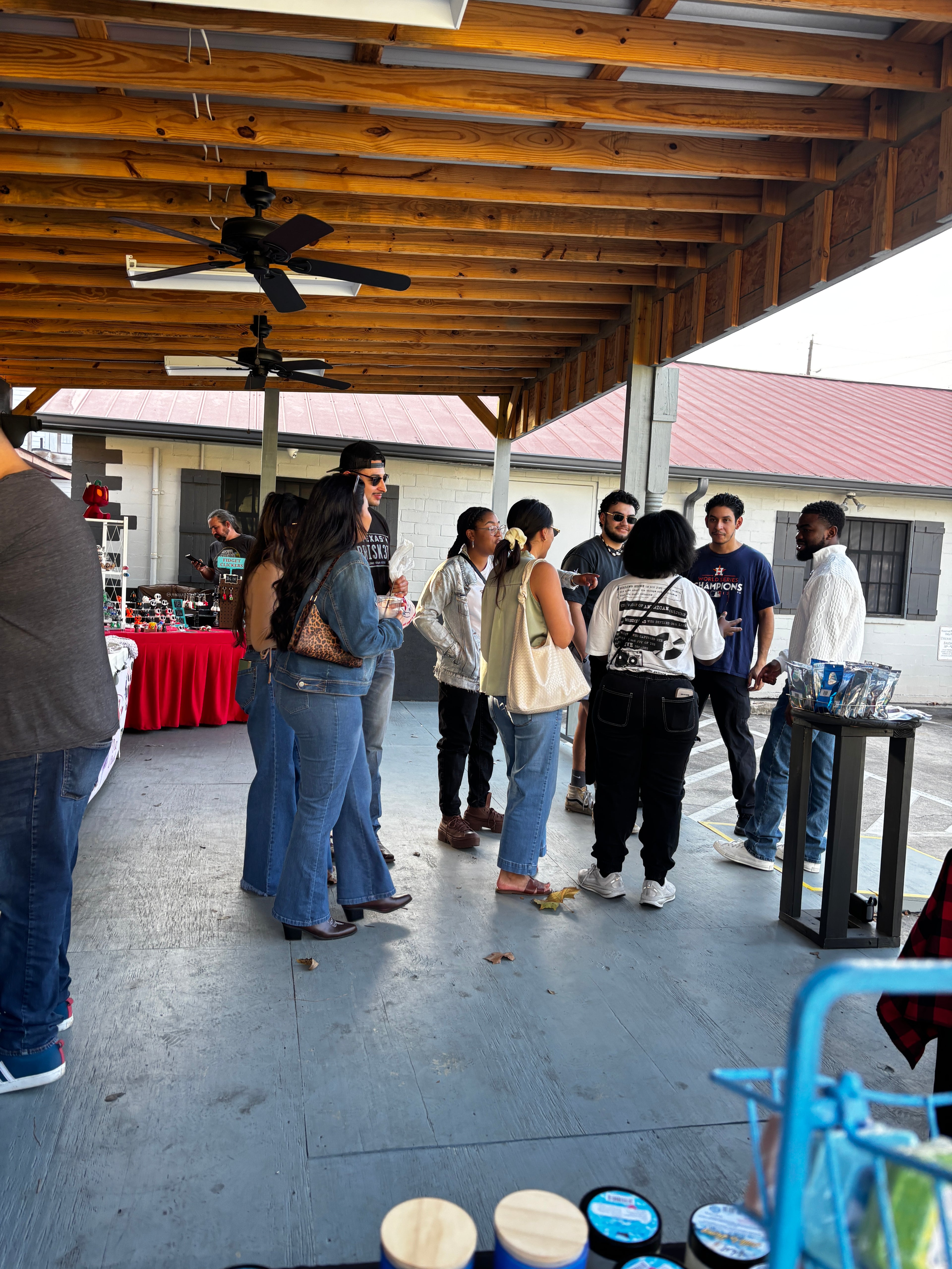 Group of people standing on The Porch with a wooden structure and streetlights in the background.