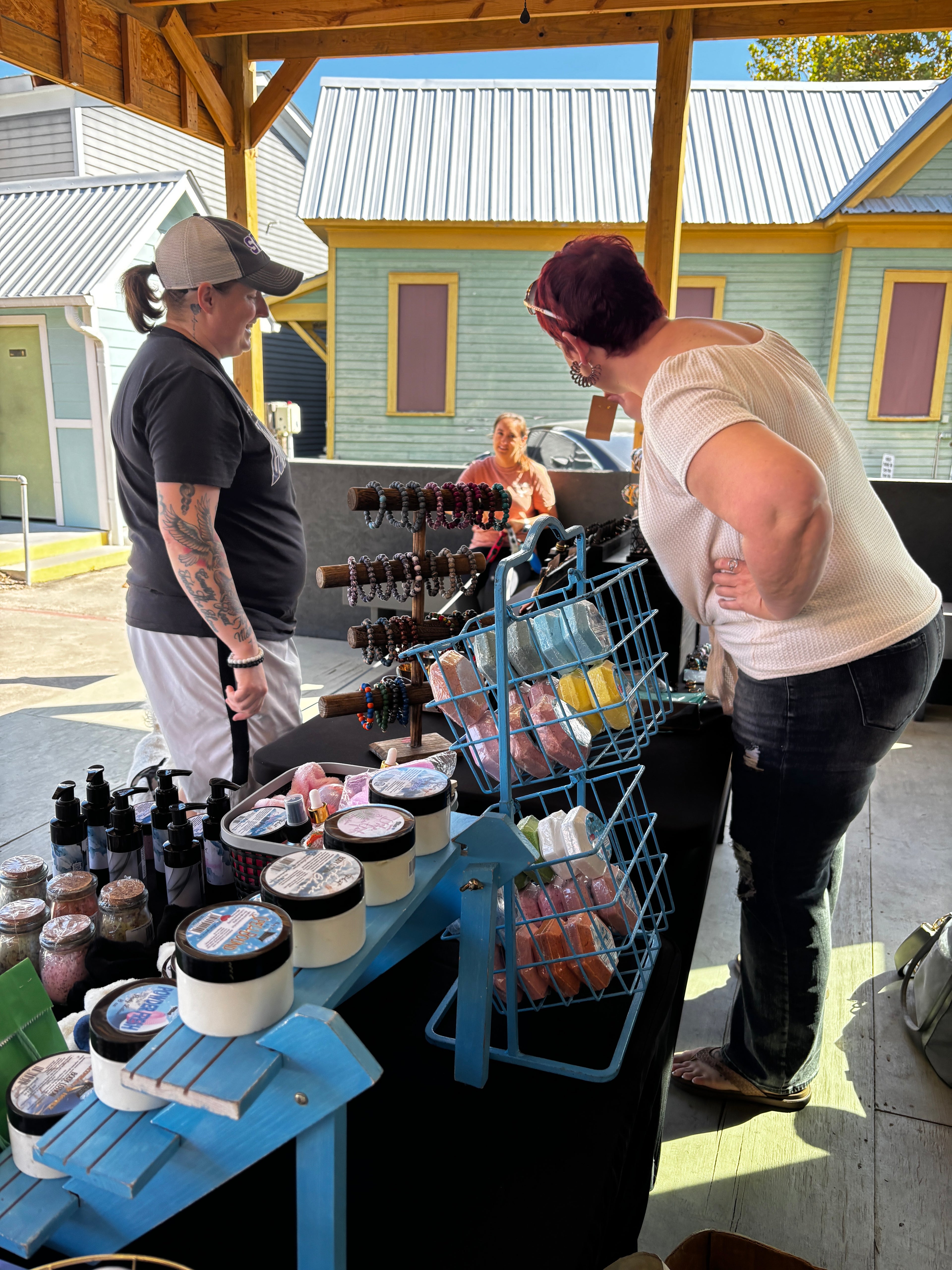 Two people talking about jewelry outdoors, with a colorful building in the background.